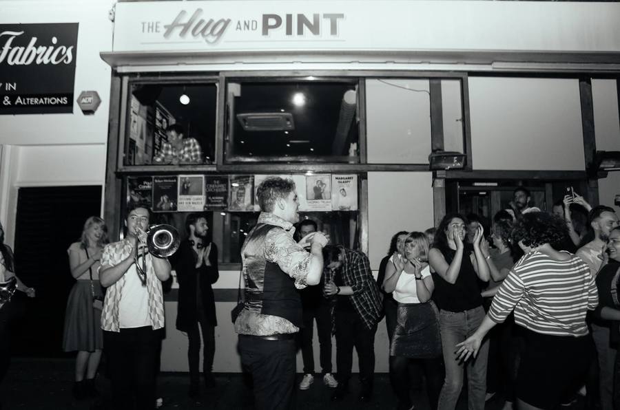 Black and white photo of a crowd outside the Hug and Pint venue in Glasgow.