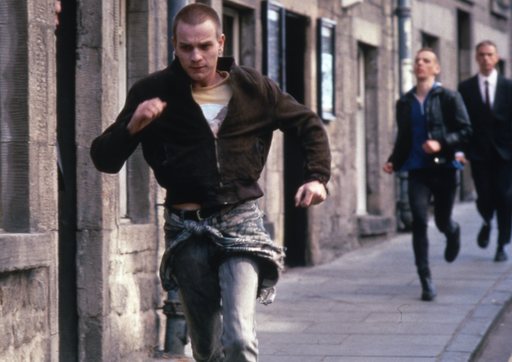 Ewan McGregor runs down a street pursued by two men, in a still from Trainspotting.