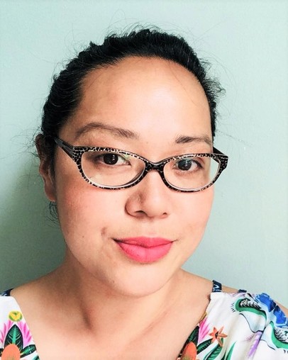 Portrait/ headshot photo of Maisie Kwan against a light green background; Maisie wears tortoiseshell glasses and a floral top.