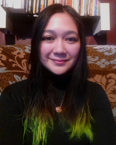 Portrait photograph of Natasha Sotsai Falconer, sitting on a brown floral print chair.