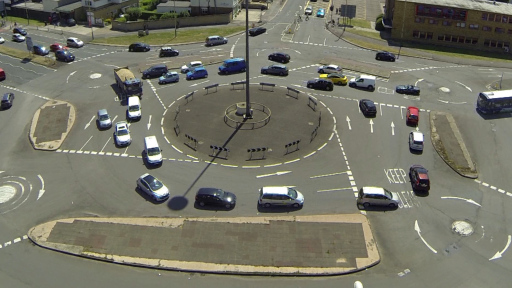 An aerial view of a group of cars gridlocked around a complex system of roundabouts. Image is a still from Aman Sandhu's artwork 'The Magic Roundabout'.