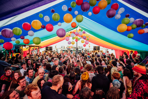 Crowds celebrated under a colorful tent surrounded by balloons and lanterns