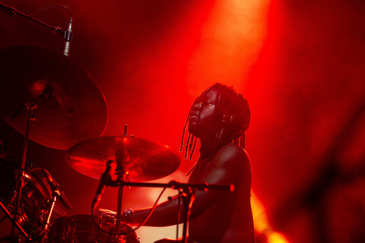 A shirtless Morgan Simpson of black midi plays his drum kit on stage at Edinburgh International Festival.