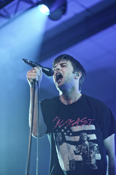 Fontaines D.C. frontman Grian Chatten singing into a microphone on stage at O2 Academy Edinburgh.