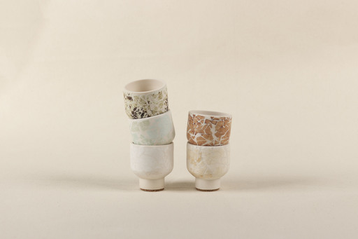 Two short stacks of pots in a variety of white and brown finishes.