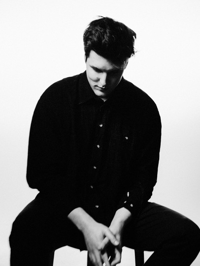 Michael Timmons sits on a stool, looking down at his feet