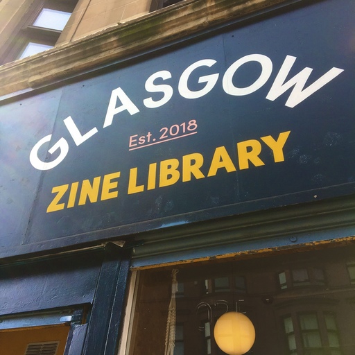 Exterior view of Glasgow Zine Library, looking upwards at white and yellow signage featuring the name of the venue.