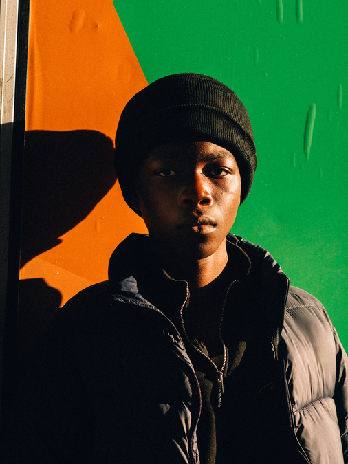 A young man standing in front of an orange and green background