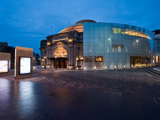 The Usher Hall in Edinburgh at night, illuminated by venue lights and posterboards.