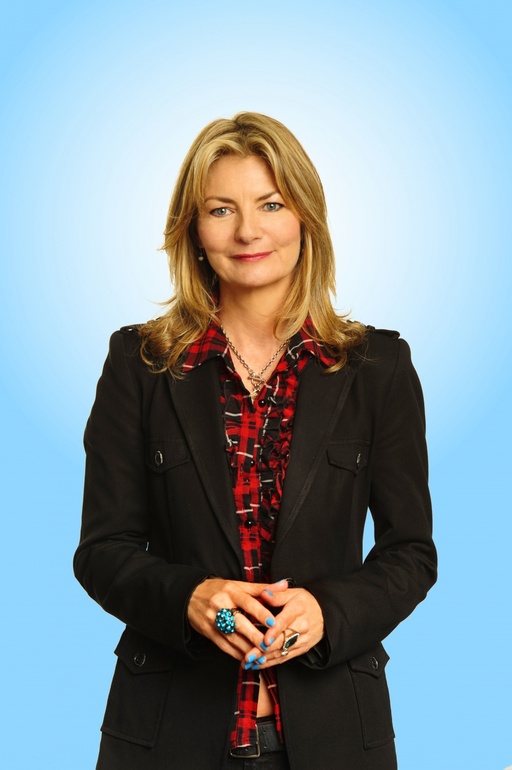 Jo Caulfield stands in front of a sky blue background.