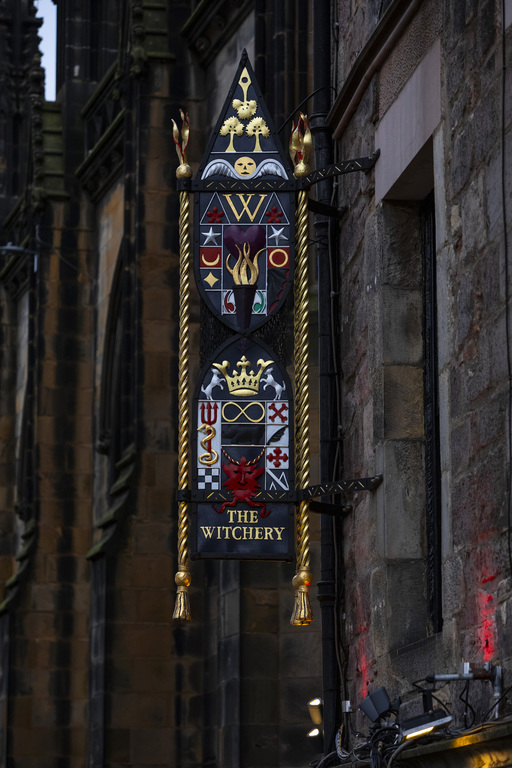 Exterior photo of The Witchery, showing a tall vertical sign covered in various heraldic imagery.