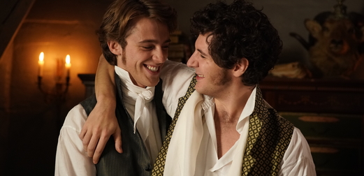 Two men, dressed in the style of the 18th and 19th century, look into one another's eyes.