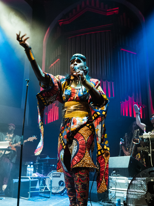 Eno Williams of Ibibio Sound Machine, on stage at St Luke's in Glasgow. Various bandmates are visible in the background.