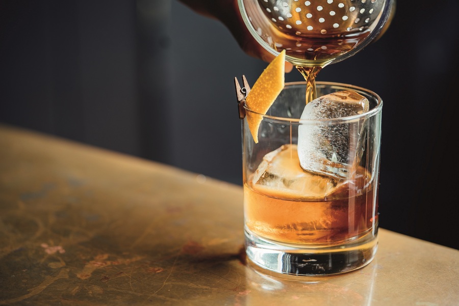 An Old Fashioned being poured into a short glass.