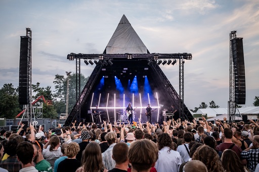 A crowd standing in front of a pyramid-shaped stage at Roskilde Festival.