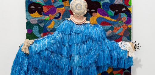 A blue frilled jacket, posed in front of an abstract artwork