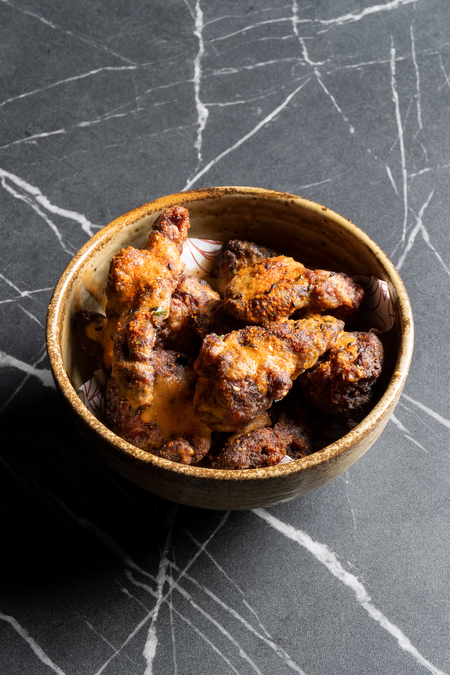 A bowl of fried chicken on a black marble-effect table.