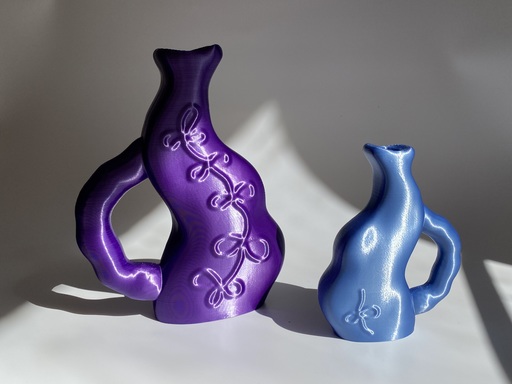 A pair of water jugs, with bumpy, warped forms. There is a large purple jug on the left, with a smaller blue jug on the right.