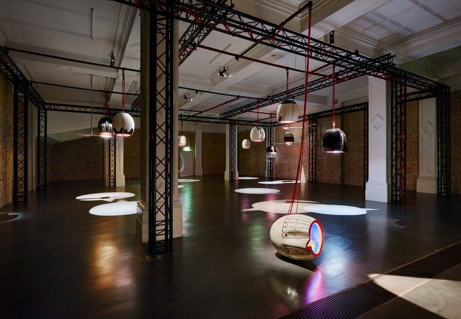 Photo of an art installation, where a series of paint-coated lamps project onto the gallery floor.