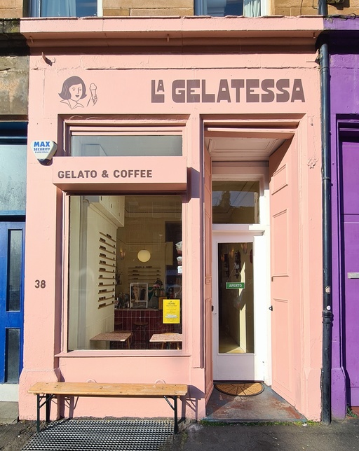 Exterior view of La Gelatessa ice cream shop. A pastel pink store front with brown signwriting and a painted logo of a woman holding an ice cream.