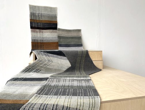 Exhibition view of artwork by Anna Lamb. Multiple pieces of overlapping grey striped textile.