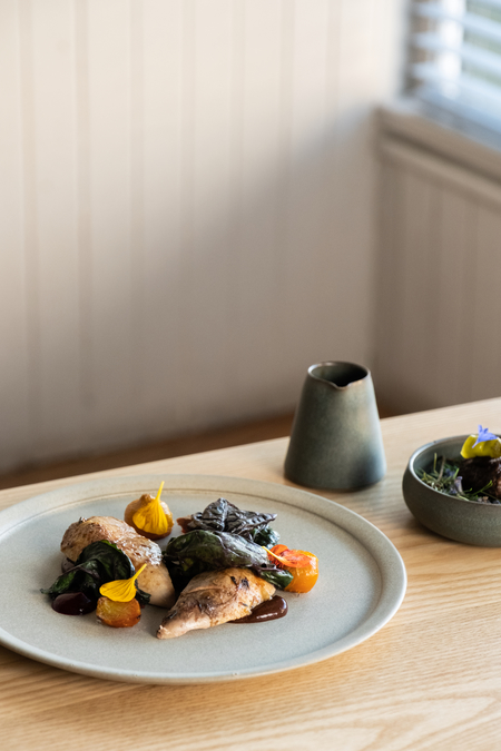 A dish of partridge and vegetable, with a side jug and plate. 