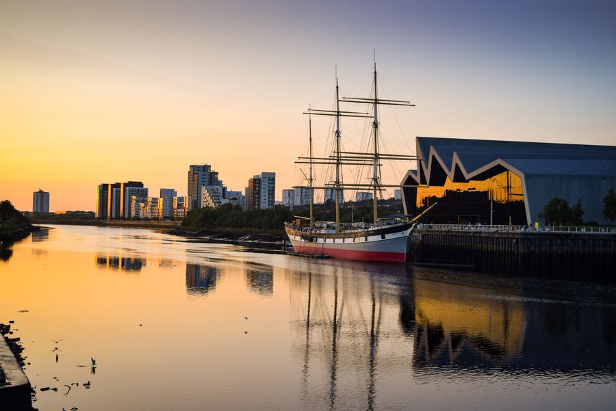 Evening view of Glasgow's riverside. A distinctive jagged building and a large ship can be seen; photo taken at sunset.