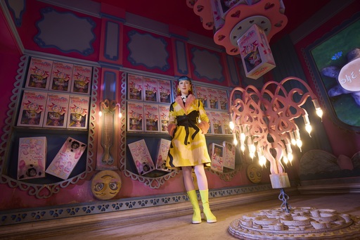 Rachel Maclean stands next to an upside-down chandelier.