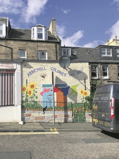 Photograph of the Abbeyhill colonies, with a painted mural on the side of a building.