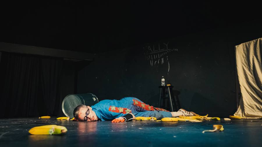 Bill O'Neill lies on the floor in a stuntman's outfit, surrounded by bananas.