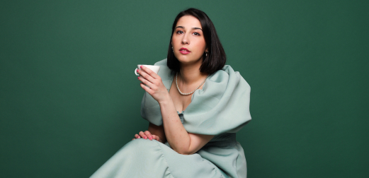 Priya Hall, holding a tea cup and wearing a teal dress.