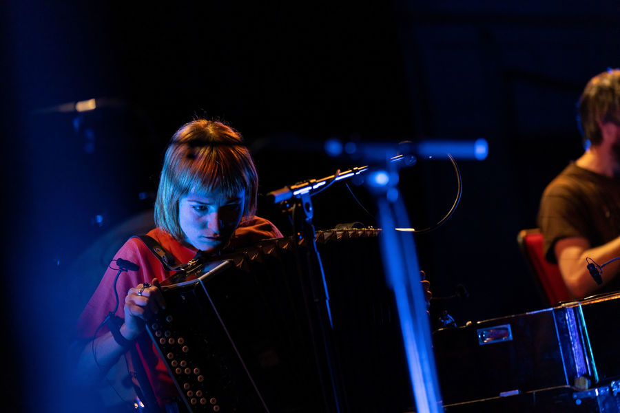 Radie Peat playing a hand organ on stage with Lankum at Edinburgh International Festival.