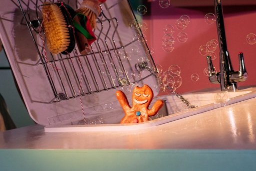 A gingerbread man waving his arms as they stand in a sink.