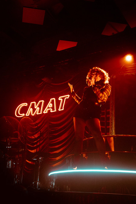 CMAT on stage, standing next to a red neon spelling out her name.