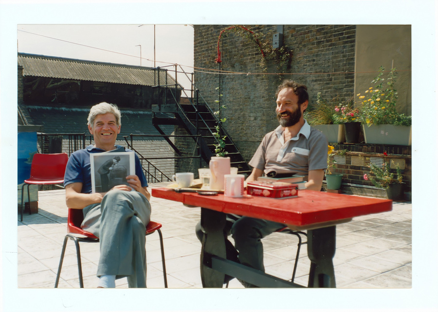 Bill Douglas and Peter Jewell sitting on plastic chairs on a rooftop.