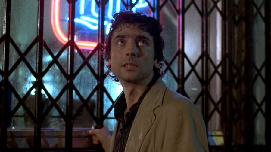 A man grips a railing outside a bar, in a still from After Hours.
