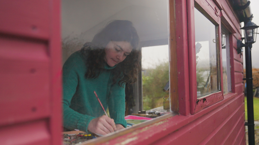 The artist Orla Stevens working by the window of her studio.