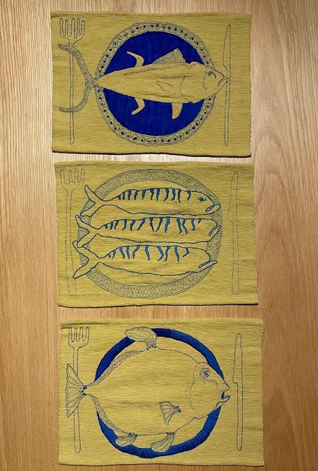 A photograph of three yellow and blue tapestries, each depicting fish.