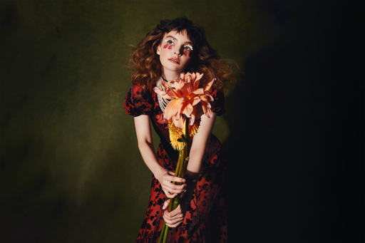 Photograph of Lauren Mayberry, holding a bunch of large flowers.