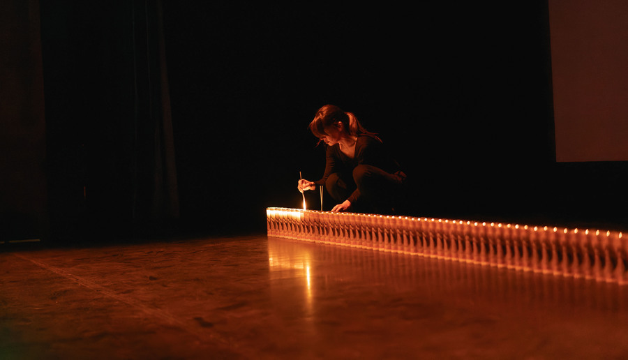 Photo of an artist lighting a long series of lights, arranged in one continuous row.