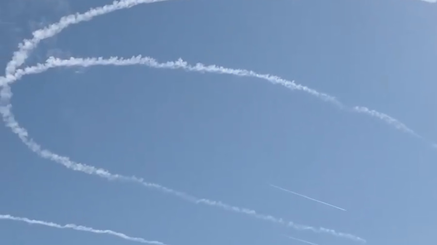 Film still of vapour trails forming across a blue sky.