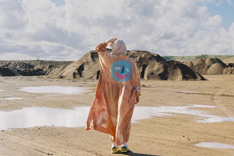 Photo of Faith Eliott standing on a beach, with their back to camera.