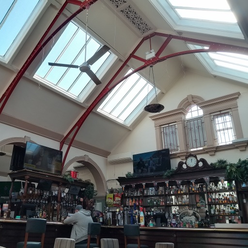 A photo of the interior of the Dean Tavern. A large ornate bar with skylights in the roof above.