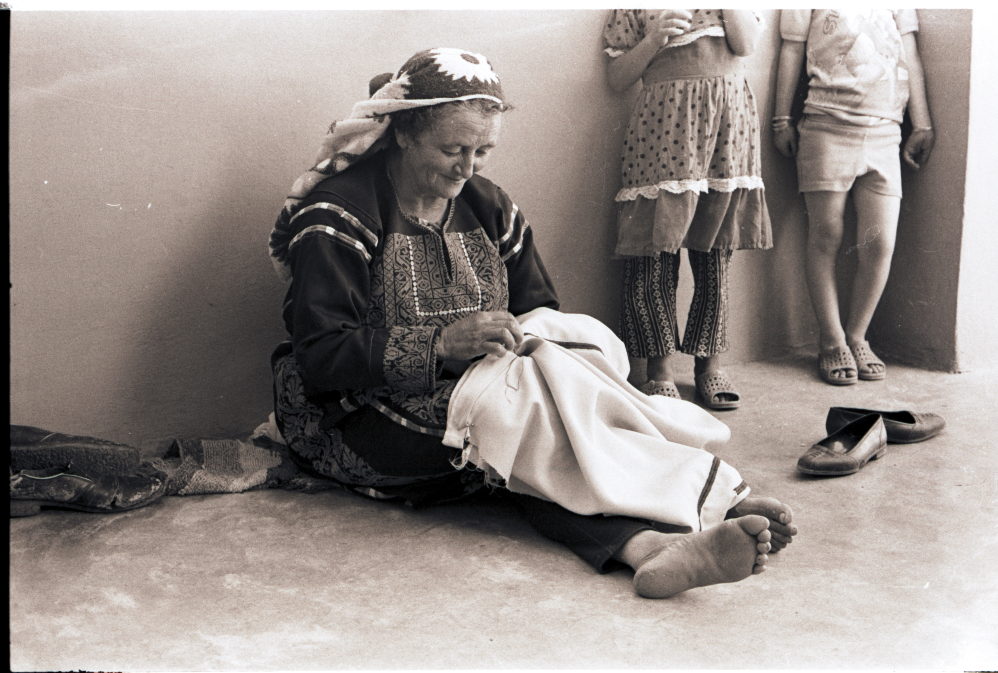 Black and white photo of a woman weaving a thobe.