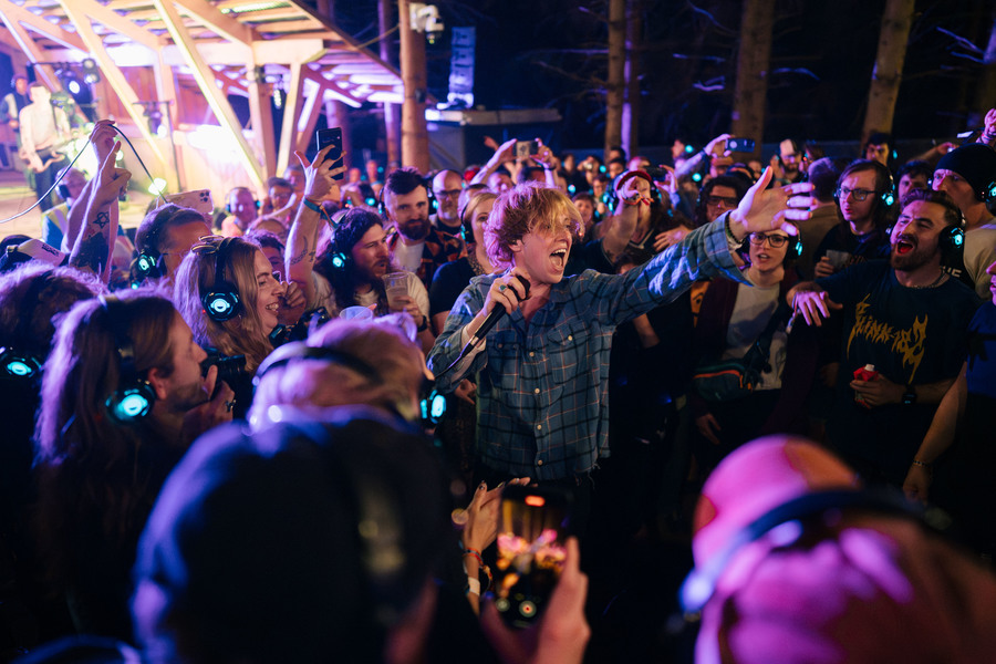 Photo of the Xcerts performing to a crowd, all of whom are wearing headphones.