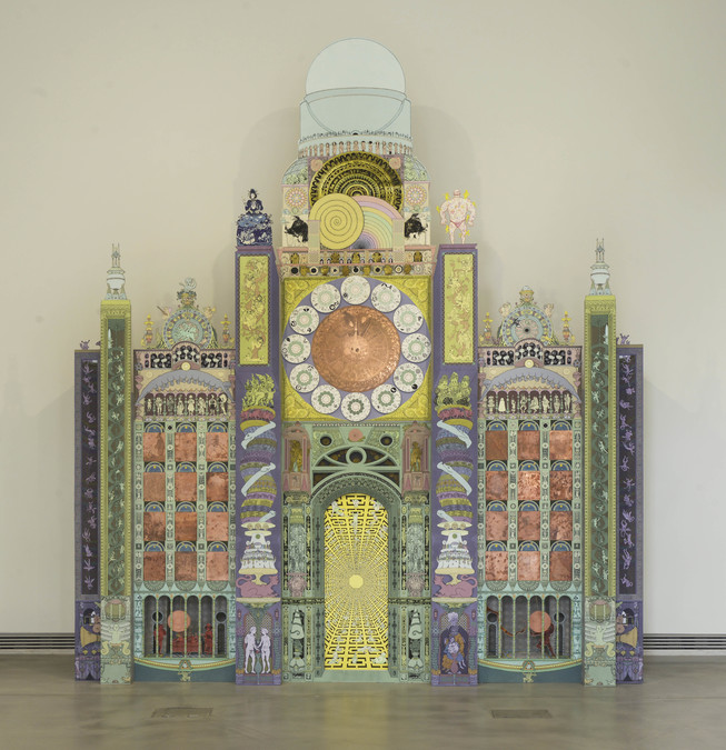 Photograph of a large ornate clock covered in multicoloured patterns.