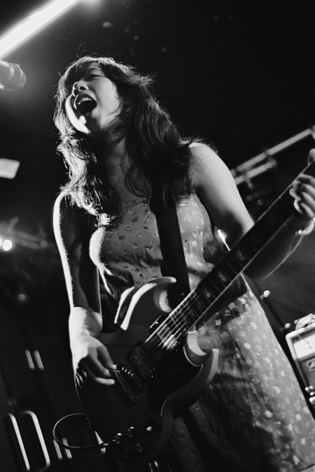 A black and white photo of Lucia de la Garza playing the guitar and singing.