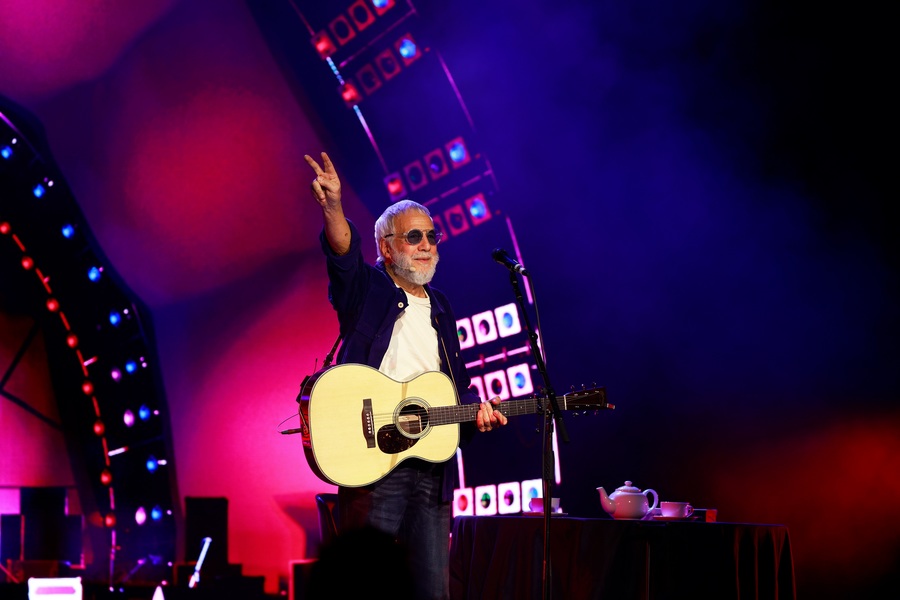 Photo of Yusuf Islam aka Cat Stevens on stage holding a guitar.