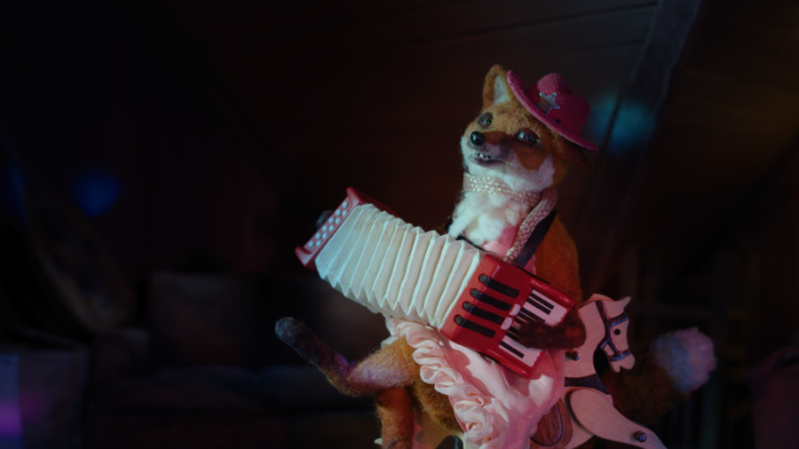 A film still showing a stuffed fox playing an accordion.