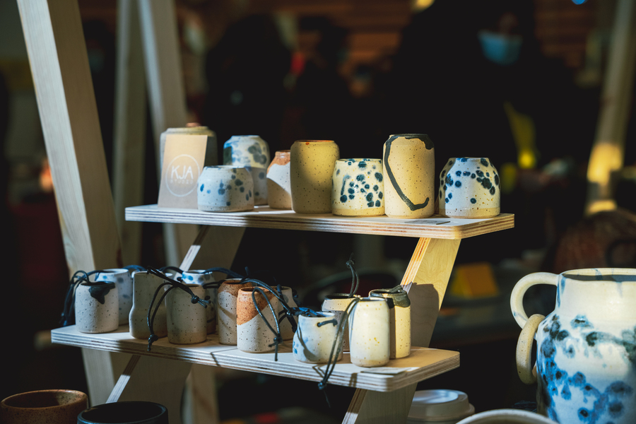 Photo of a display of mugs and ceramics, with fairy lights draped across the shelves.